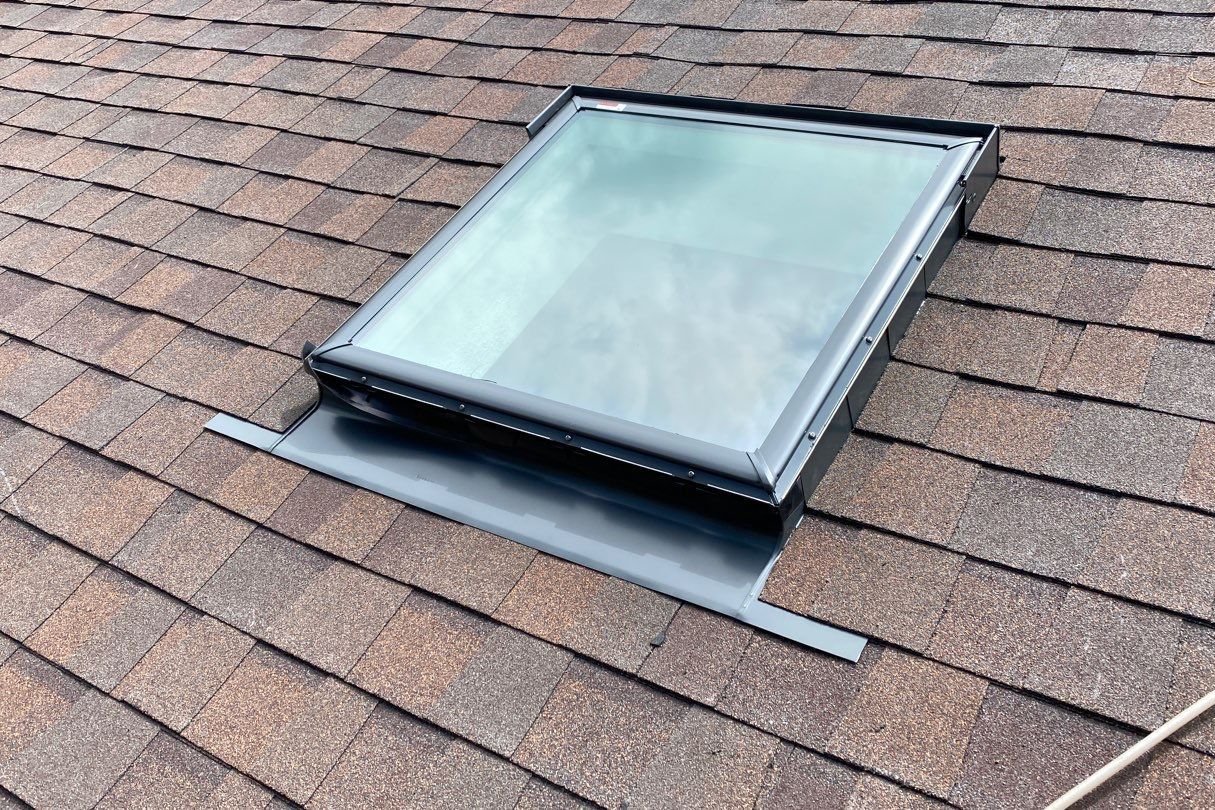 A roofer installing plywood decking on a roof before installing a skylight.