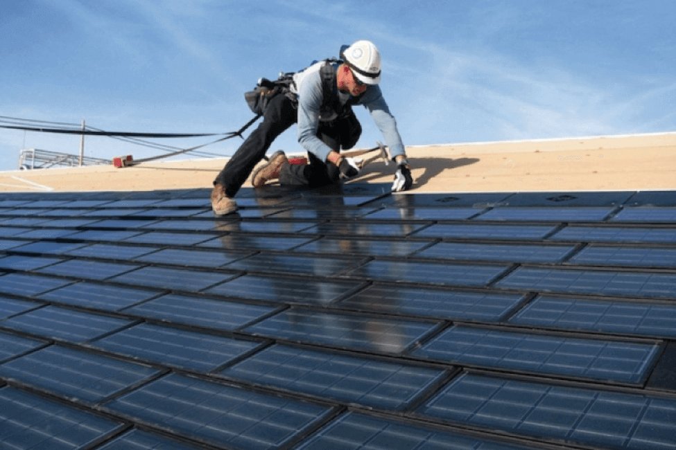 A roofer installing what appears to be integrated solar roofing panels